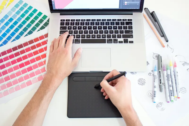 Graphiste qui dessine sur tablette graphique, nuancier de couleurs à côté